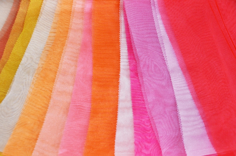 May include: A collection of sheer fabric swatches in various shades of orange, pink, and red. The fabric is arranged in a rainbow pattern, with the lightest colors at the top and the darkest colors at the bottom.