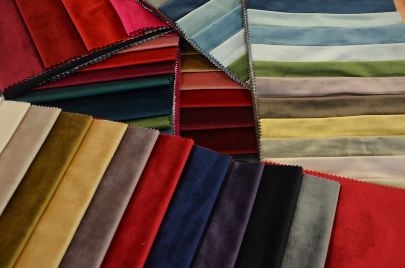 May include: A selection of fabric swatches in various colours and textures, including red, blue, green, brown, and beige. The swatches are arranged in a fan shape, with the edges of the fabric overlapping.