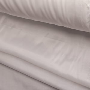 Puede incluir: Tela blanca doblada en capas, mostrando la textura suave y el brillo sedoso.