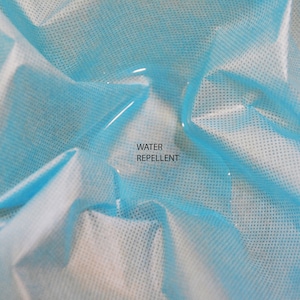 May include: A close-up of a light blue fabric with a water droplet on it. The fabric is textured and has the words "WATER REPELLENT" printed on it.