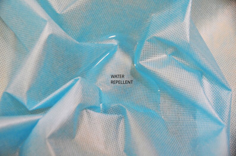 May include: A close-up of a light blue fabric with a water droplet on it. The fabric is textured and has the words "WATER REPELLENT" printed on it.