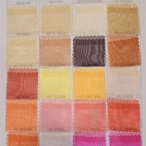 May include: A color chart of sheer fabric swatches in various shades of white, yellow, orange, pink, and red. The swatches are labeled with numbers and color names, such as "White", "Ivory", "Champagne", "Banana", "Gold", "Mocha", "Brown", "Cinnamon", "Rust", "Yellow", "Mustard", "Peach", "Orange", "Coral", "D/Orange", "Pumpkin", "Pink", "Hot Pink", and "Fuschia".