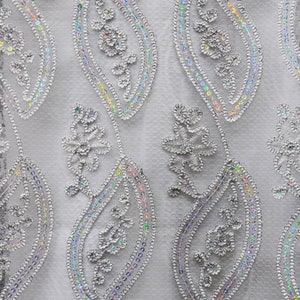 May include: White fabric with a silver sequin and thread embroidery design. The design features paisley shapes and floral motifs.