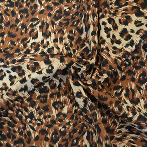 Op de afbeelding: Bruin, zwart en wit luipaardprint stof met een draaiend patroon.