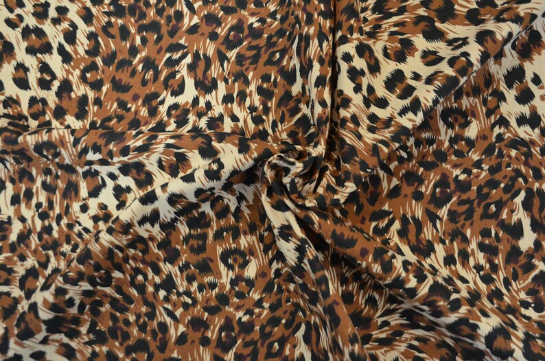 Op de afbeelding: Bruin, zwart en wit luipaardprint stof met een draaiend patroon.