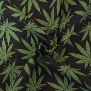 May include: Black fabric with a repeating pattern of green cannabis leaves.