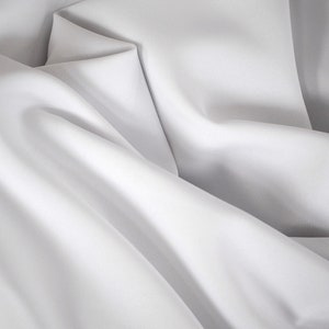 May include: White fabric with soft folds and wrinkles. The fabric is smooth and silky.