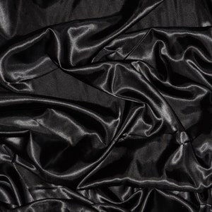 May include: A close-up of black satin fabric with soft, flowing folds and a smooth, luxurious texture.