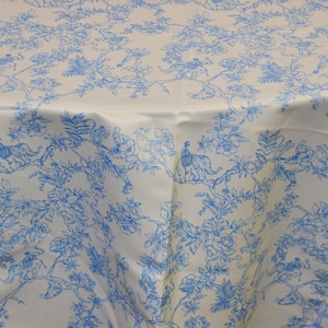 May include: White tablecloth with a blue floral pattern featuring peacocks and elephants. The pattern is repeated throughout the fabric.