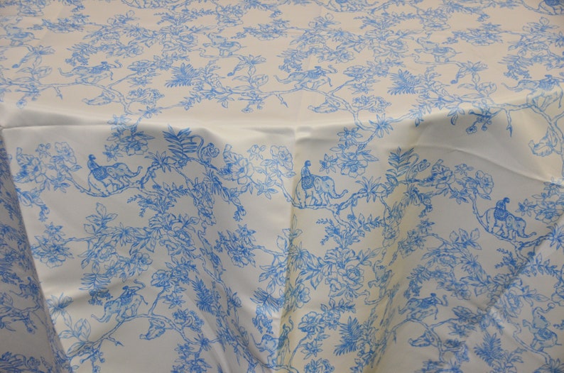 May include: White tablecloth with a blue floral pattern featuring peacocks and elephants. The pattern is repeated throughout the fabric.
