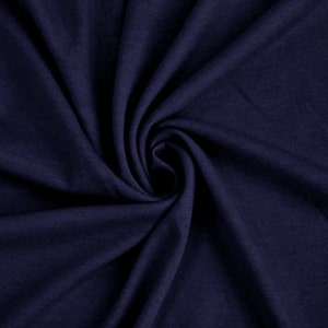 May include: A close-up of a dark blue fabric with a soft, smooth texture. The fabric is folded and draped, creating a sense of movement and flow.