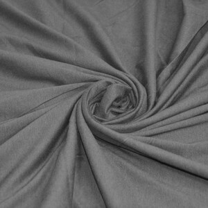 May include: A close-up of a gray fabric with a soft, smooth texture. The fabric is folded and twisted, creating a swirling pattern.