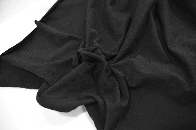 Peut inclure: Tissu noir avec une texture douce et lisse. Le tissu est pli&eacute; et drap&eacute;, montrant ses plis et ses rides naturels.