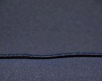 May include: Close-up of a dark blue fabric with a seam running across the middle.