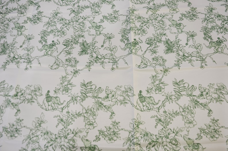 May include: White fabric with a repeating pattern of green leafy branches, flowers, and elephants with riders. The elephants are facing left and right.