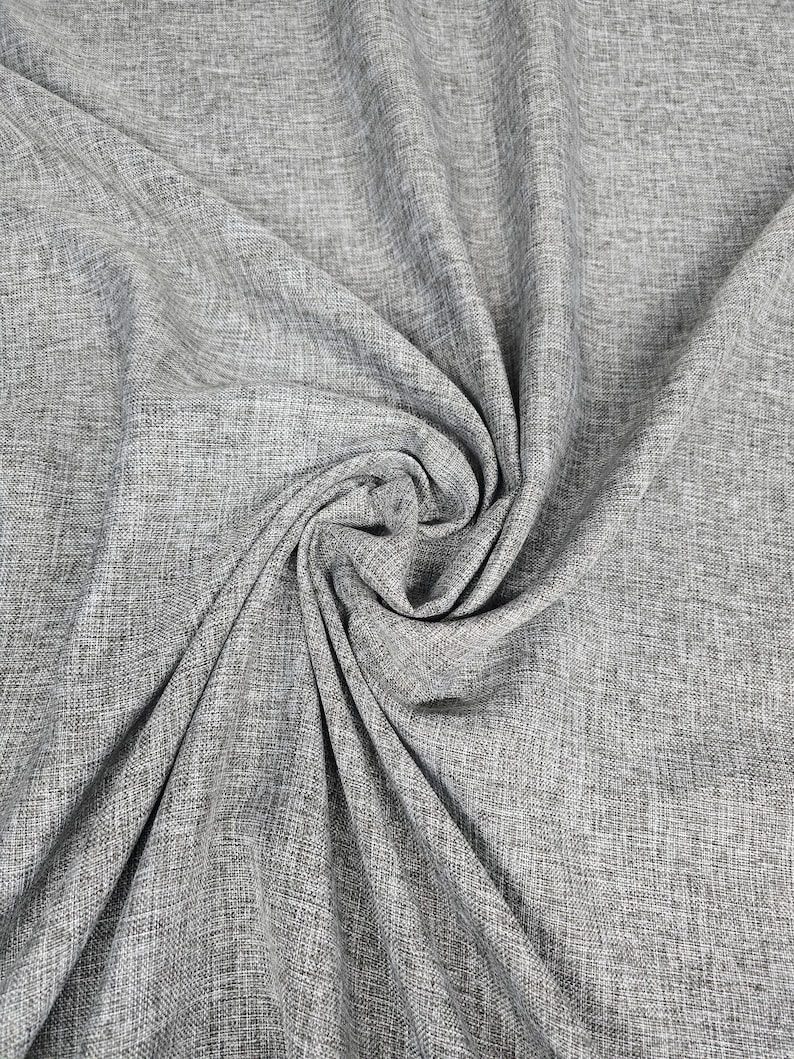 May include: Close-up of a gray fabric with a textured weave. The fabric is draped and folded, creating shadows and highlights that emphasize its texture. The material appears to be a medium-weight fabric, suitable for various sewing projects.