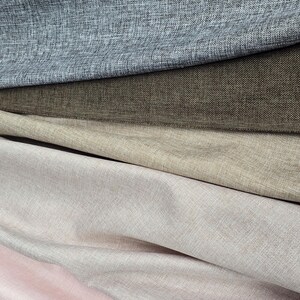 May include: Close-up of layered fabric samples in shades of gray, brown, beige, and pink. The textiles have a textured appearance, suggesting a linen or similar weave. The image showcases a variety of neutral colors suitable for home decor or fashion.