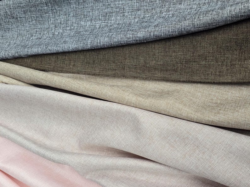 May include: Close-up of layered fabric samples in shades of gray, brown, beige, and pink. The textiles have a textured appearance, suggesting a linen or similar weave. The image showcases a variety of neutral colors suitable for home decor or fashion.