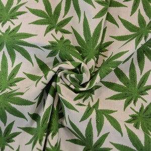 May include: Green cannabis leaf print fabric. The fabric is white with a repeating pattern of green cannabis leaves.