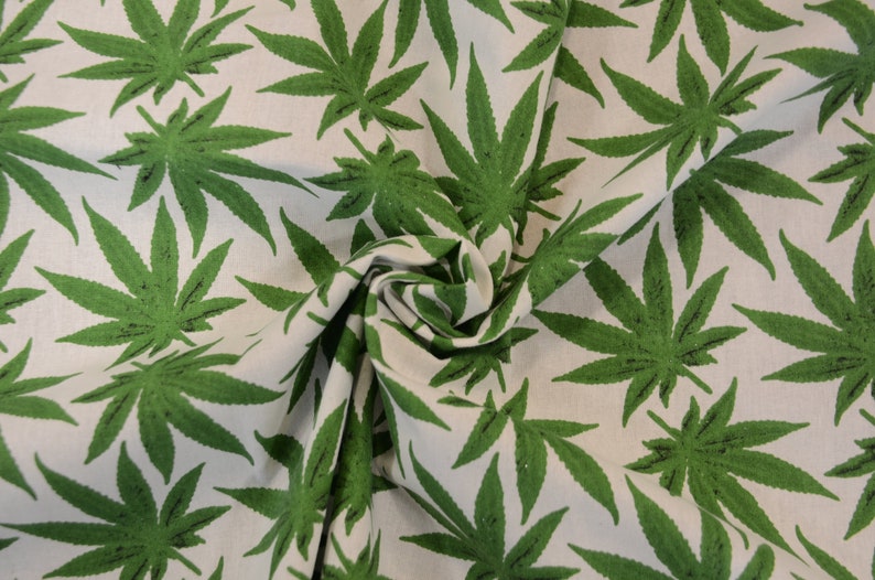 May include: Green cannabis leaf print fabric. The fabric is white with a repeating pattern of green cannabis leaves.