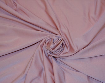 May include: A close-up of a soft, smooth, dusty rose-colored fabric. The fabric is draped and folded, creating a swirling pattern.