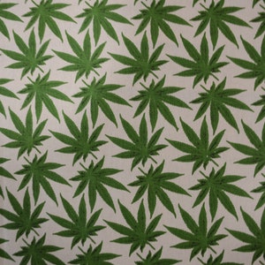 May include: Green cannabis leaf pattern fabric. The fabric is white with a repeating pattern of green cannabis leaves.