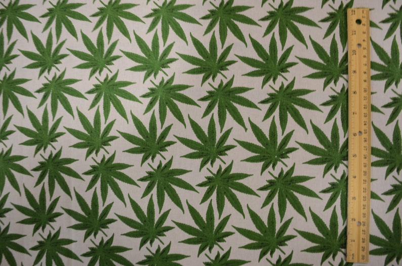 May include: Green cannabis leaf pattern fabric. The fabric is white with a repeating pattern of green cannabis leaves.