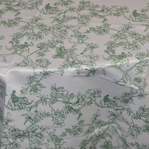 May include: White tablecloth with a green floral pattern featuring elephants, monkeys, and birds. The pattern is repeated throughout the fabric.