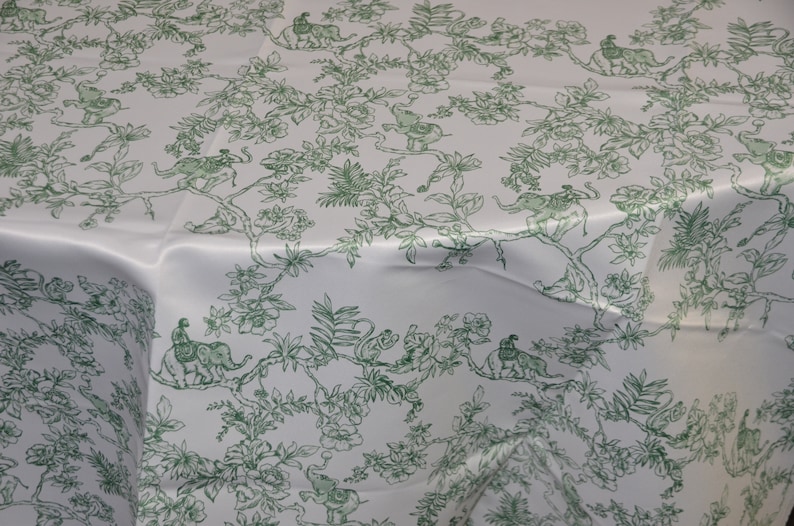 May include: White tablecloth with a green floral pattern featuring elephants, monkeys, and birds. The pattern is repeated throughout the fabric.