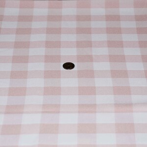 May include: A pink and white gingham fabric with a small coin in the centre.