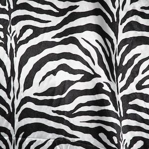 May include: Black and white zebra print fabric with a wrinkled texture.