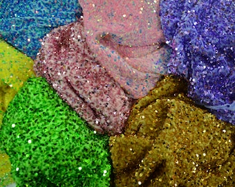 May include: A collection of colorful fabrics, each covered in shimmering sequins. The fabrics are arranged in a circular pattern, with colors including teal, pink, purple, gold, green, and yellow. The sequins catch the light, creating a sparkling effect.