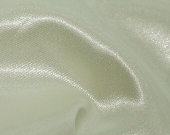 May include: A close-up of a smooth, off-white satin fabric with a subtle sheen. The fabric is draped and folded, creating soft curves and folds.