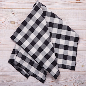May include: A black and white checkered kitchen towel folded on a white wooden surface.