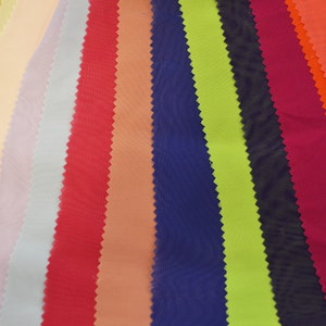 May include: A collection of fabric swatches in various colors, including yellow, peach, lavender, light blue, red, coral, navy blue, lime green, black, burgundy, orange, and red. The fabric swatches are arranged in a fan shape.