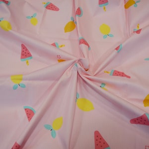 May include: Pink fabric with a repeating pattern of watermelon slices and lemons. The watermelon slices are red, green, and black, and the lemons are yellow with green leaves.
