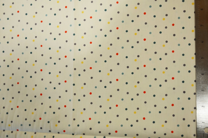 May include: A white fabric with a repeating pattern of small, colorful polka dots. The dots are in shades of red, yellow, blue, and gray.