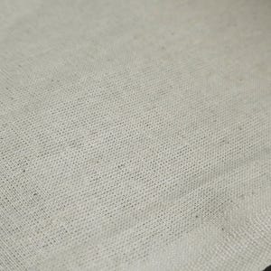 May include: Close-up of a plain, off-white fabric with a subtle woven texture.