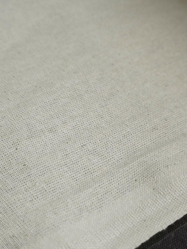 May include: Close-up of a plain, off-white fabric with a subtle woven texture.