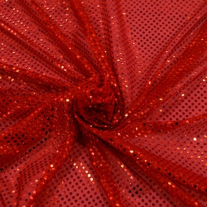 May include: Red fabric with a shiny, dotted pattern. The fabric is folded and draped, showing the texture and sparkle of the material.