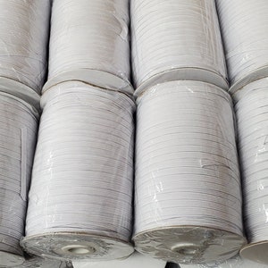 May include: Multiple spools of white elastic string wound tightly on cardboard cores. The elastic is packaged in clear plastic.