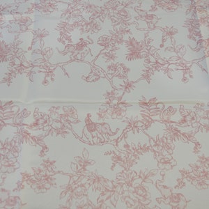May include: White fabric with a pink floral pattern featuring elephants, monkeys, and peacocks. The pattern is repeated throughout the fabric.