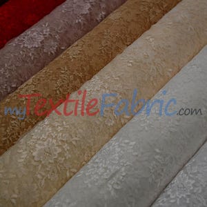 May include: Close-up of several rolls of floral lace fabric in various colors, including red, mauve, gold, beige, and white. The fabric is tightly rolled, showcasing the delicate floral pattern. The website myTextileFabric.com is visible.