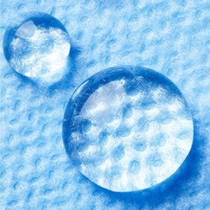 May include: Close-up of three water droplets on a blue textured surface. The droplets are clear and round, with a slight shimmer.