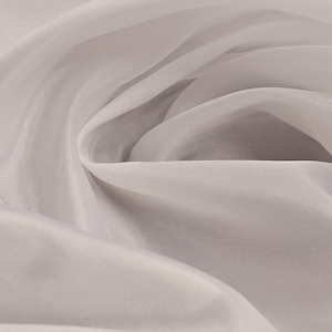 Puede incluir: Tela blanca transparente con una textura suave y fluida. La tela est&aacute; drapeada y doblada, creando un aspecto liso y elegante.