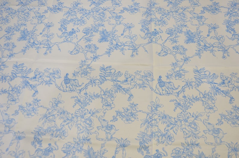 May include: White fabric with a blue floral pattern featuring elephants and monkeys. The pattern is repeated throughout the fabric.