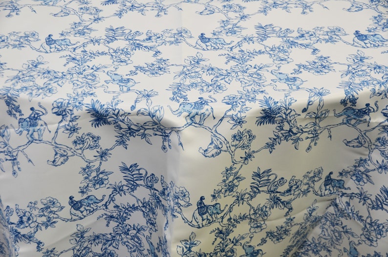 May include: White tablecloth with a blue and white floral pattern featuring elephants and monkeys. The pattern is reminiscent of a traditional toile design.
