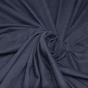 May include: A close-up of a dark blue fabric with a soft, smooth texture. The fabric is folded and draped in a way that creates a swirling pattern.
