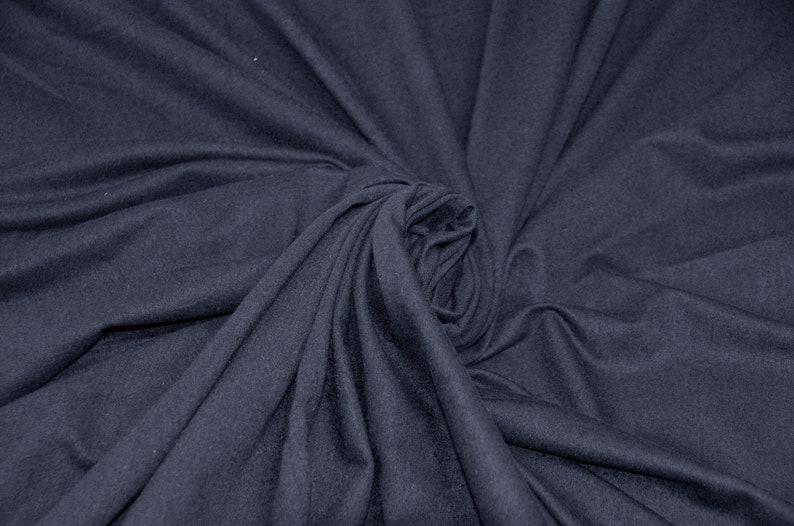 May include: A close-up of a dark blue fabric with a soft, smooth texture. The fabric is folded and draped in a way that creates a swirling pattern.