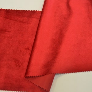 May include: A close-up of a red velvet fabric. The fabric is folded in half and the edges are visible.